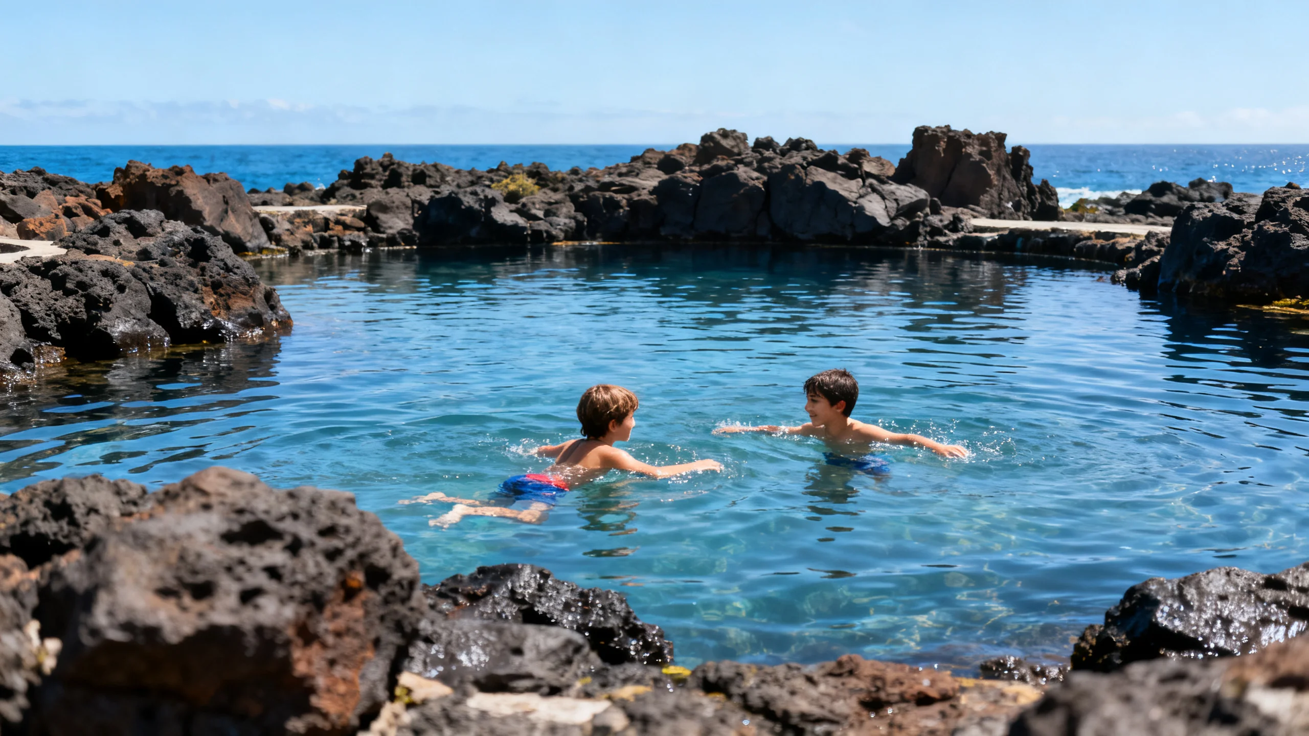 Children swimming in the calm natural lava-rock sea pools at Porto Moniz on a bright day