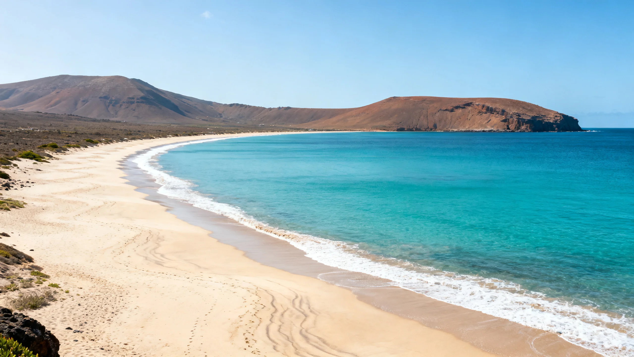 The long pale-sand beach of Porto Santo curving along a calm turquoise bay under clear sky