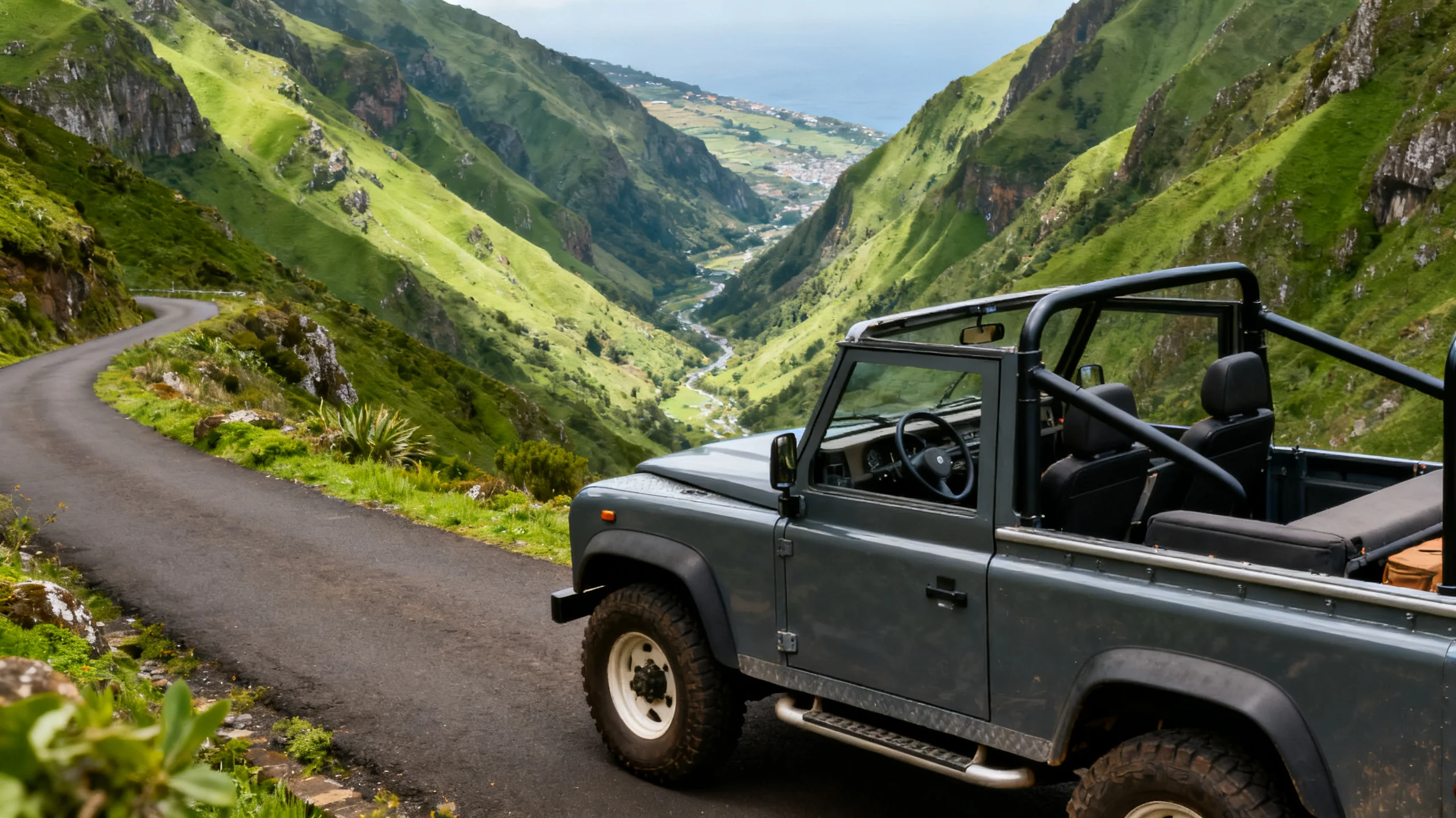Un jeep 4x4 descapotable en una estrecha carretera de montaña en Madeira con crestas verdes y un valle detrás